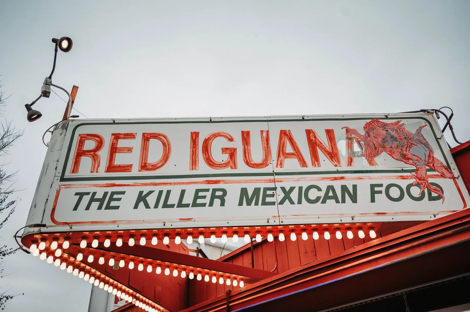 Brightly lit Red Iguana sign highlighting Mexican food at a renowned restaurant.